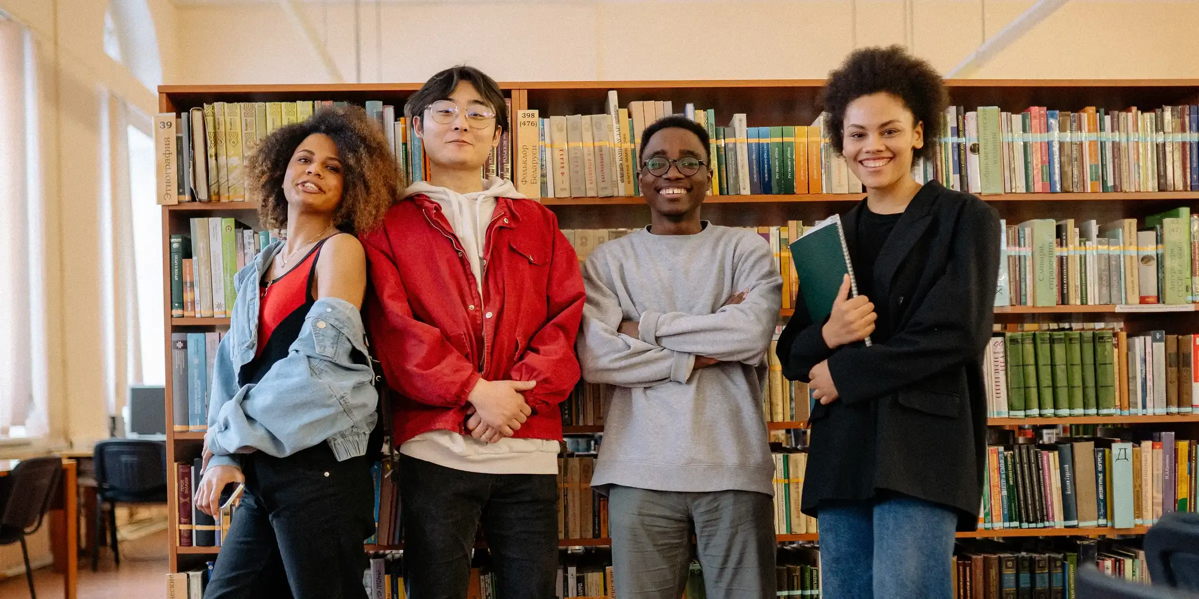 Students standing in front of book shelf in library