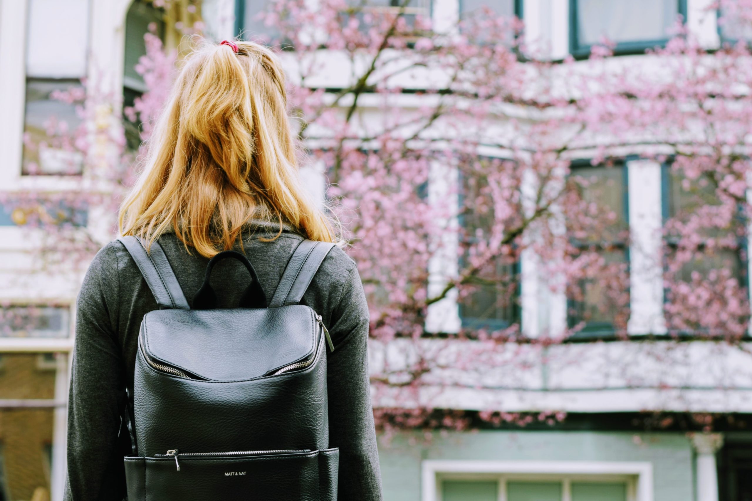 student with bookbag on college campus in spring