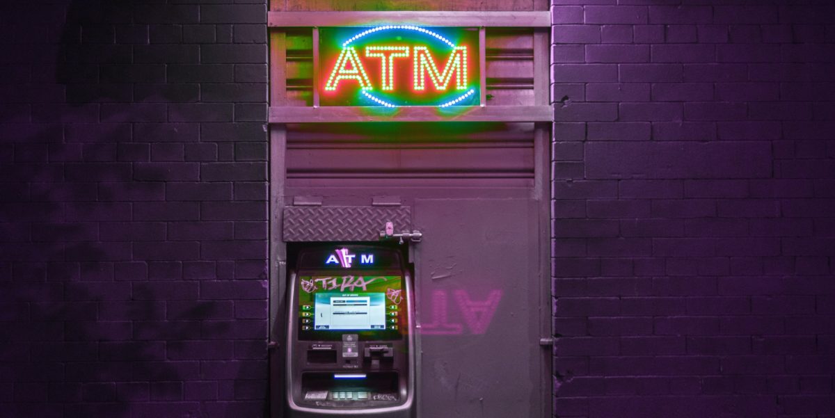 An outdoor ATM with a neon light.