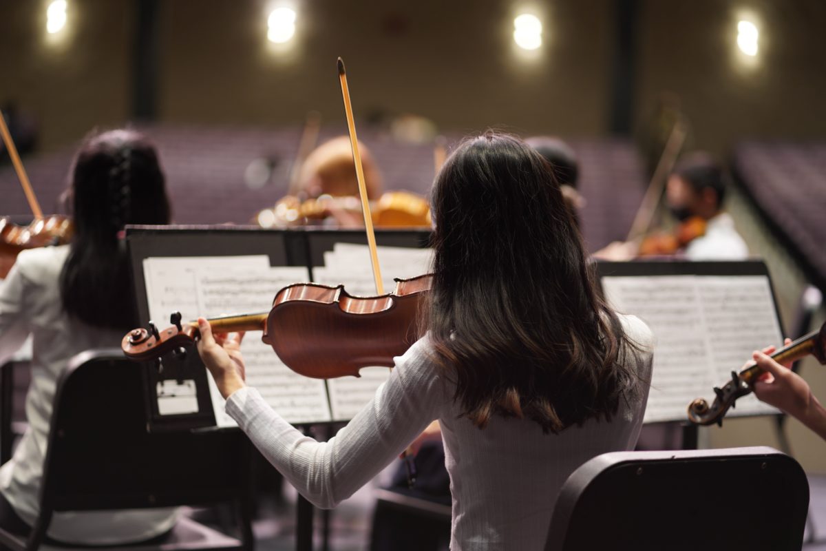 Students playing the violin in an orchestra.