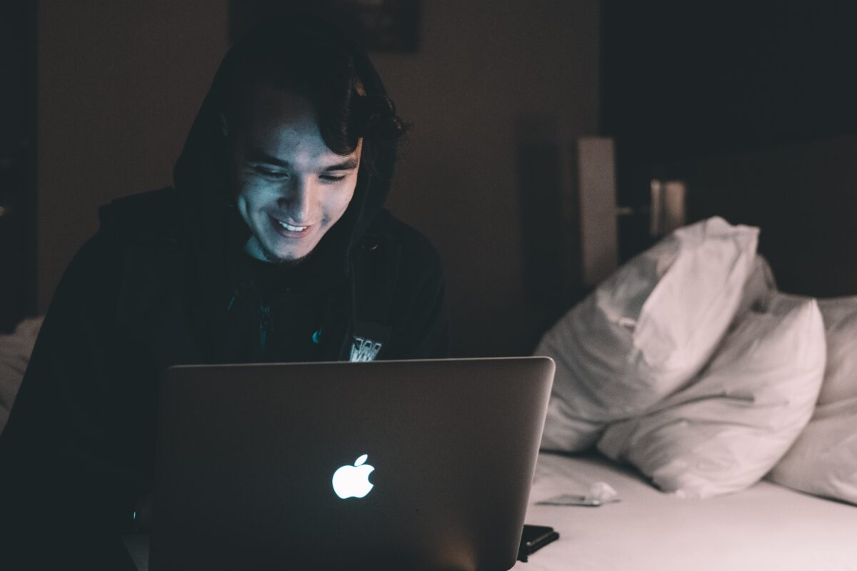 A young man smiling at his computer.