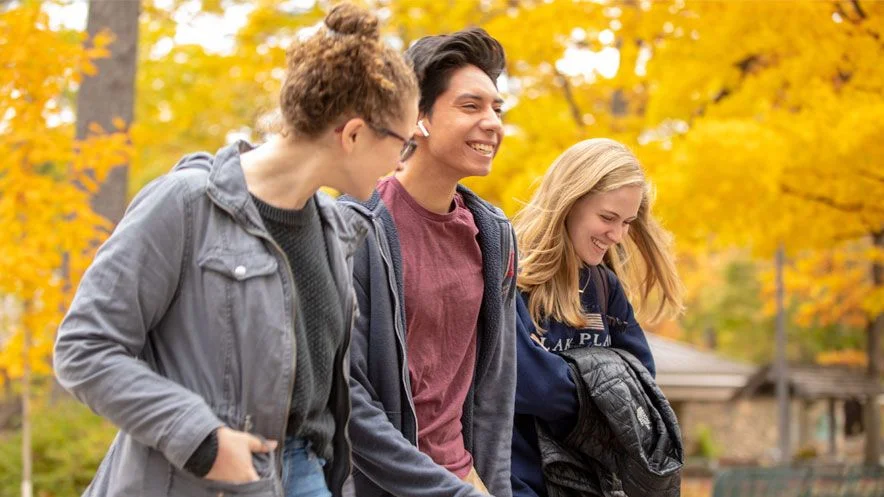 Three students walk together outside during the fall.