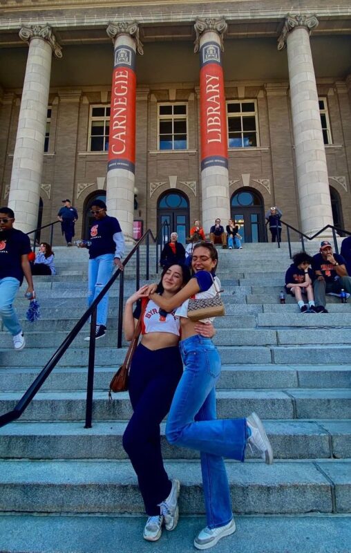 Two young women hugging on the steps of Carnegie Library.