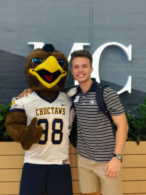 A young man poses with Mississippi College's mascot.